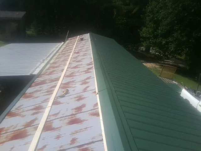 Old rusted panels beside newly installed green metal roofing — Wind Damage Roof Repair by Roofing Brothers in Harlowton