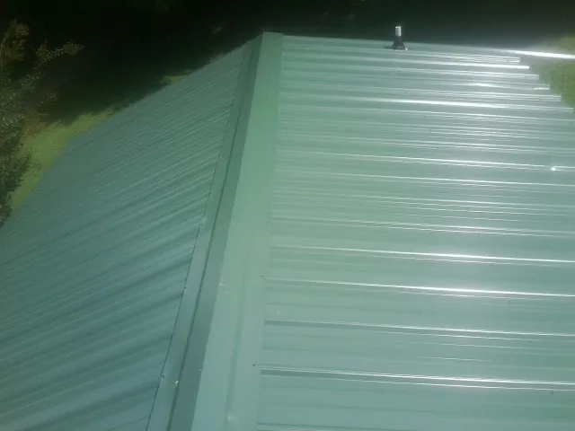 New green metal panels meeting at the ridge of a roof — Flat Roof Repair work by our crew in Harlowton