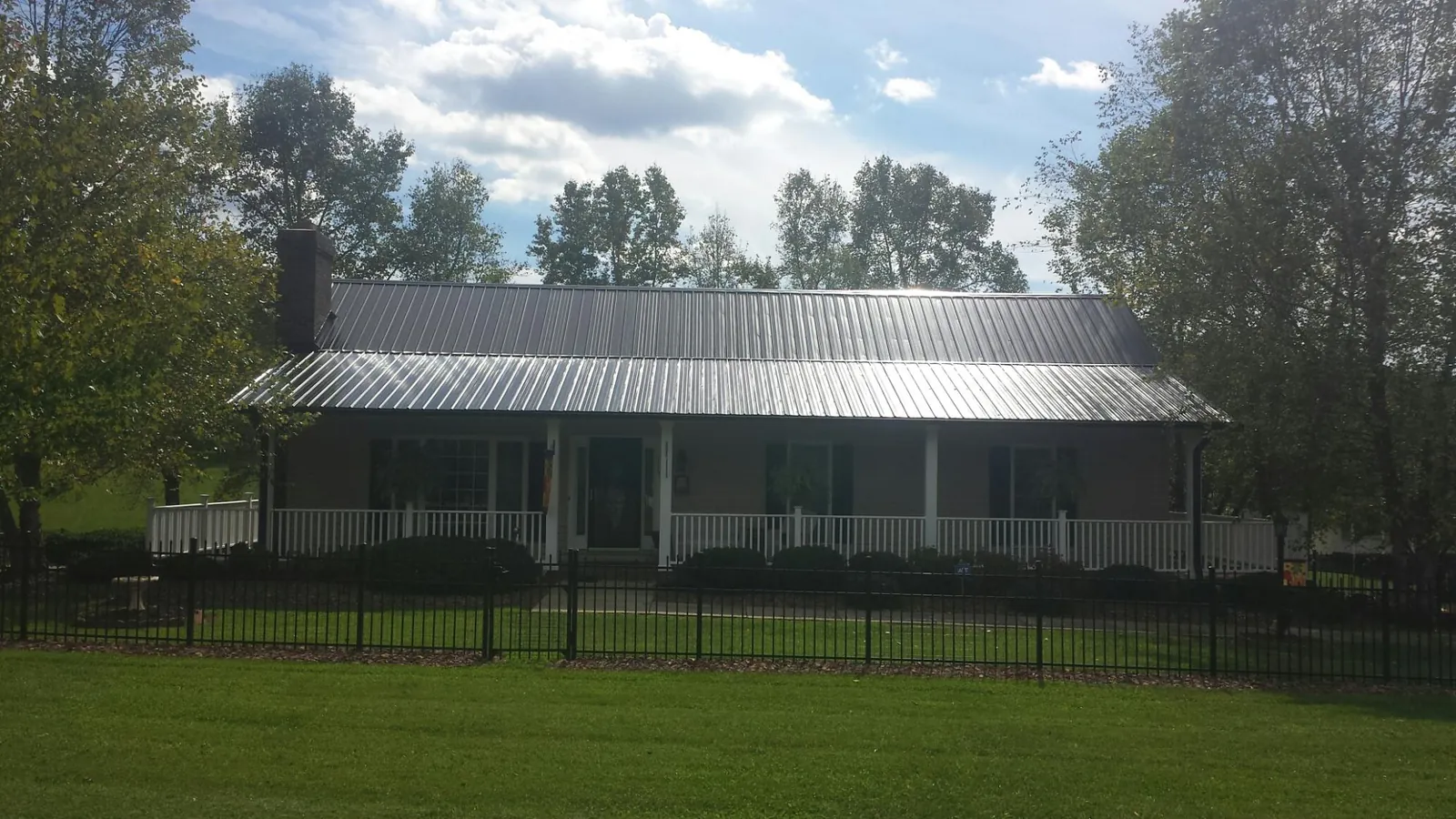 Gray metal roof on a brick ranch with a full width front porch — Gutter Guard Installation work by our crew in Harlowton