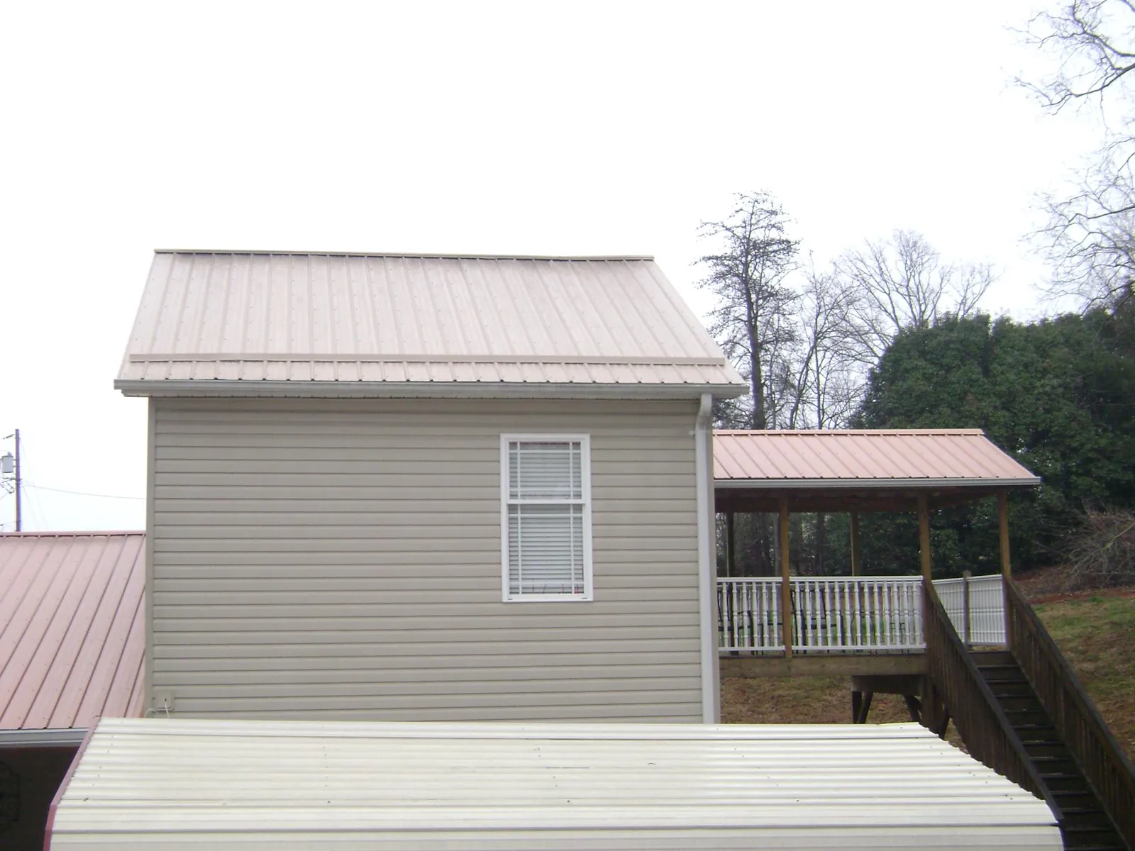 Tan metal roofs on a two story addition and attached porch, from a Roof Replacement job in Harlowton
