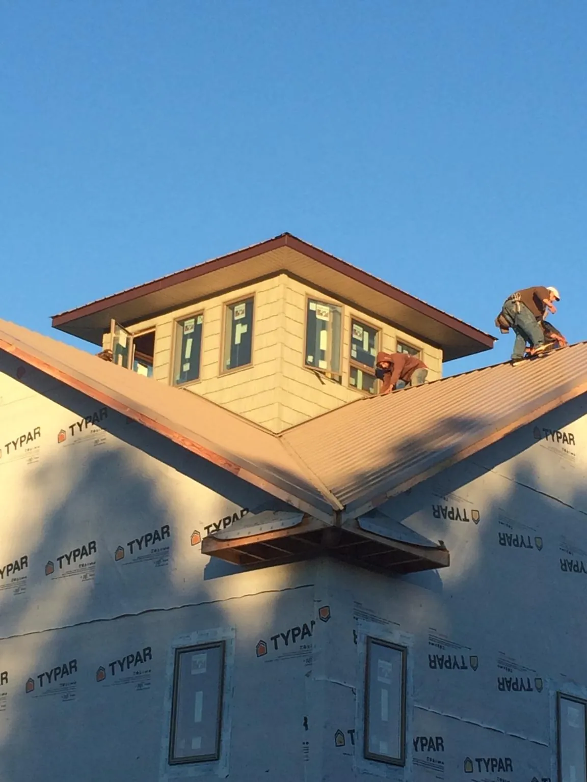 Roofers working around a rooftop cupola on a new metal roof at sunset — Roof Waterproofing in Harlowton by Roofing Brothers